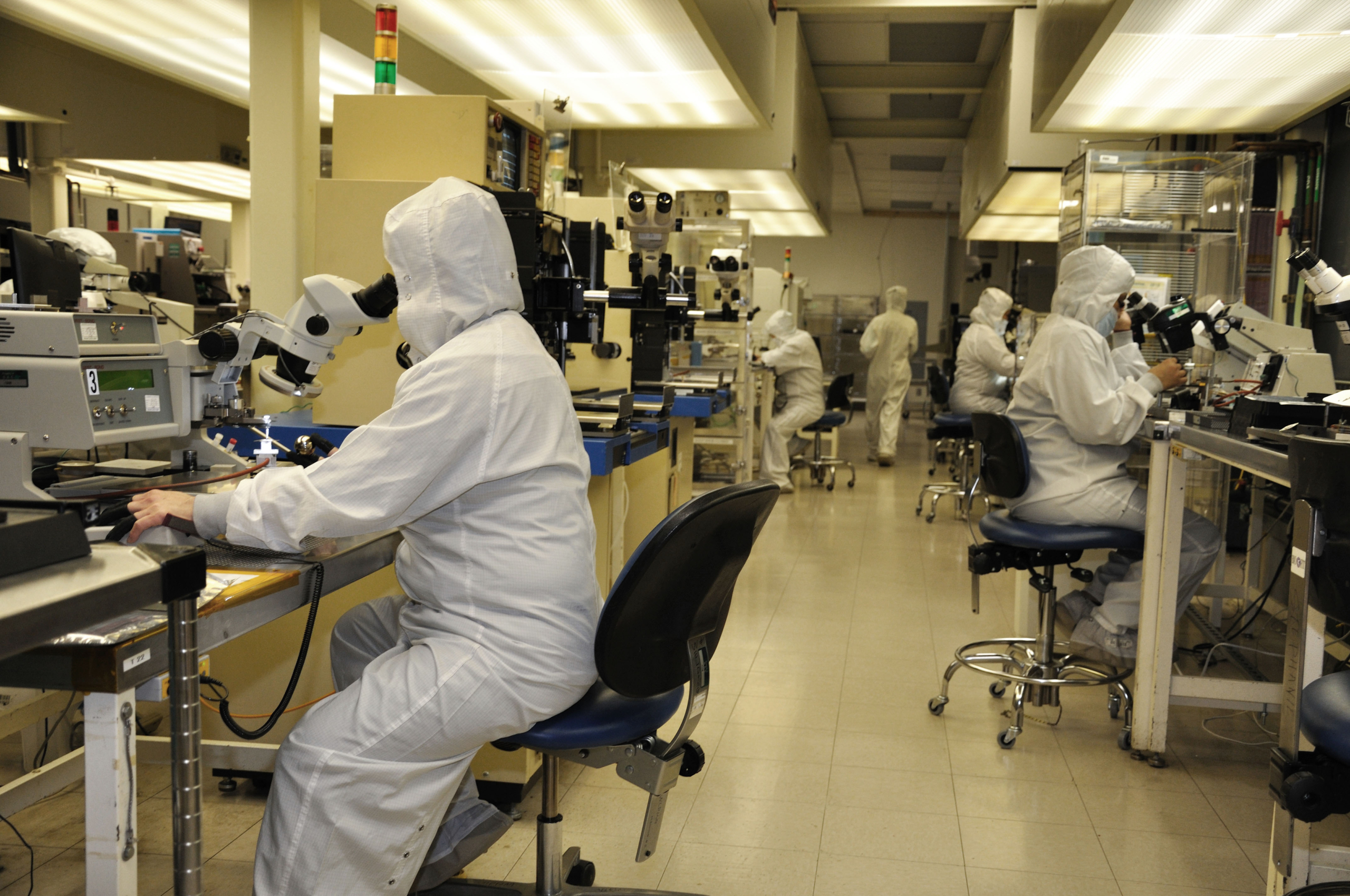 Golden Altos- Operator-testing components using a microscope-donning a laboratory gown